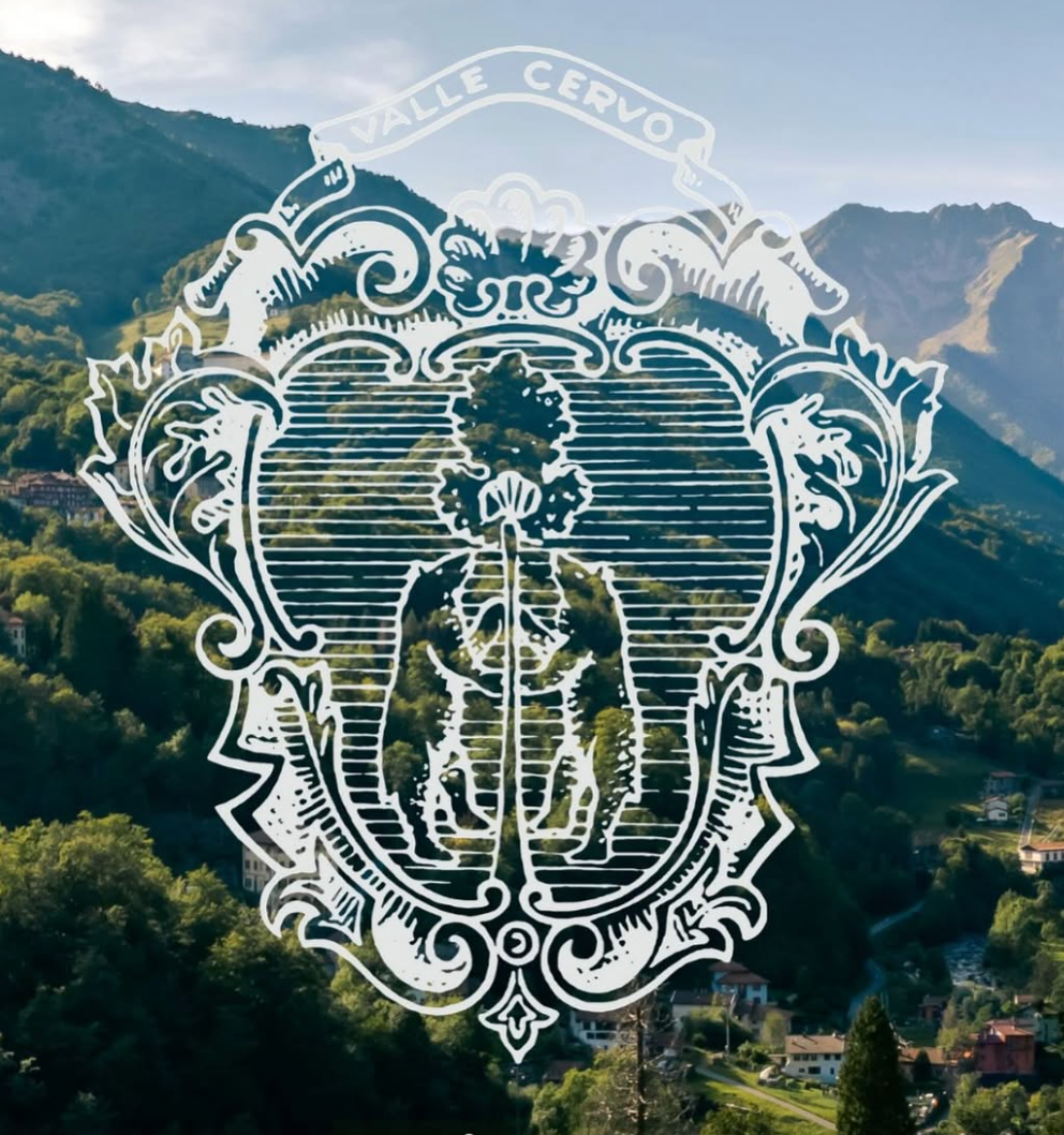 Decorative emblem with 'Valle Cervo' text over a mountainous landscape.