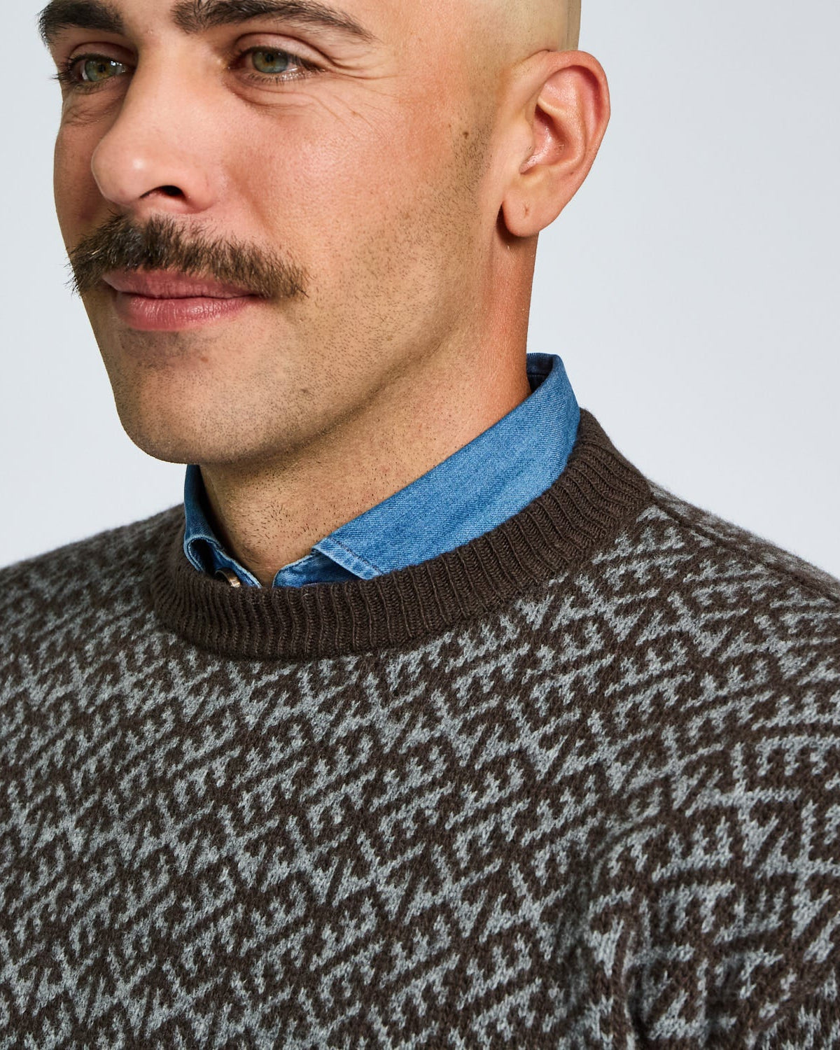 Man wearing a patterned sweater with a plain background