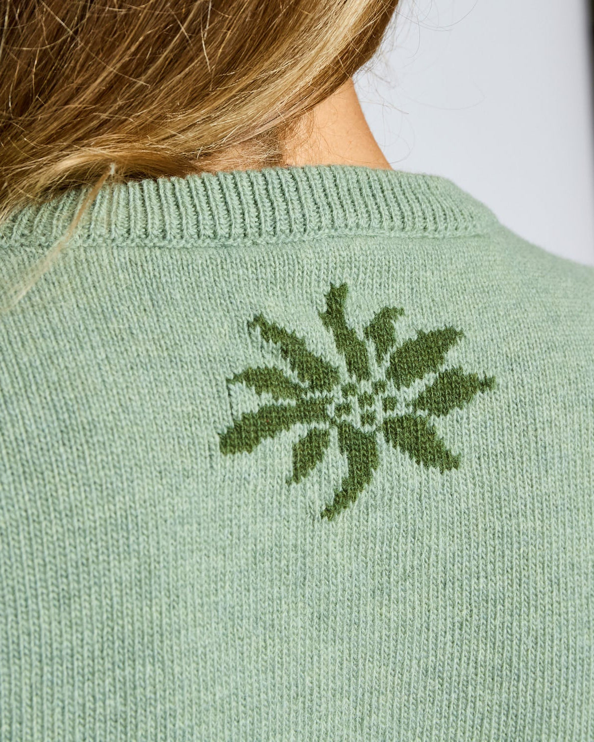 Green knitted sweater with a floral pattern on the back