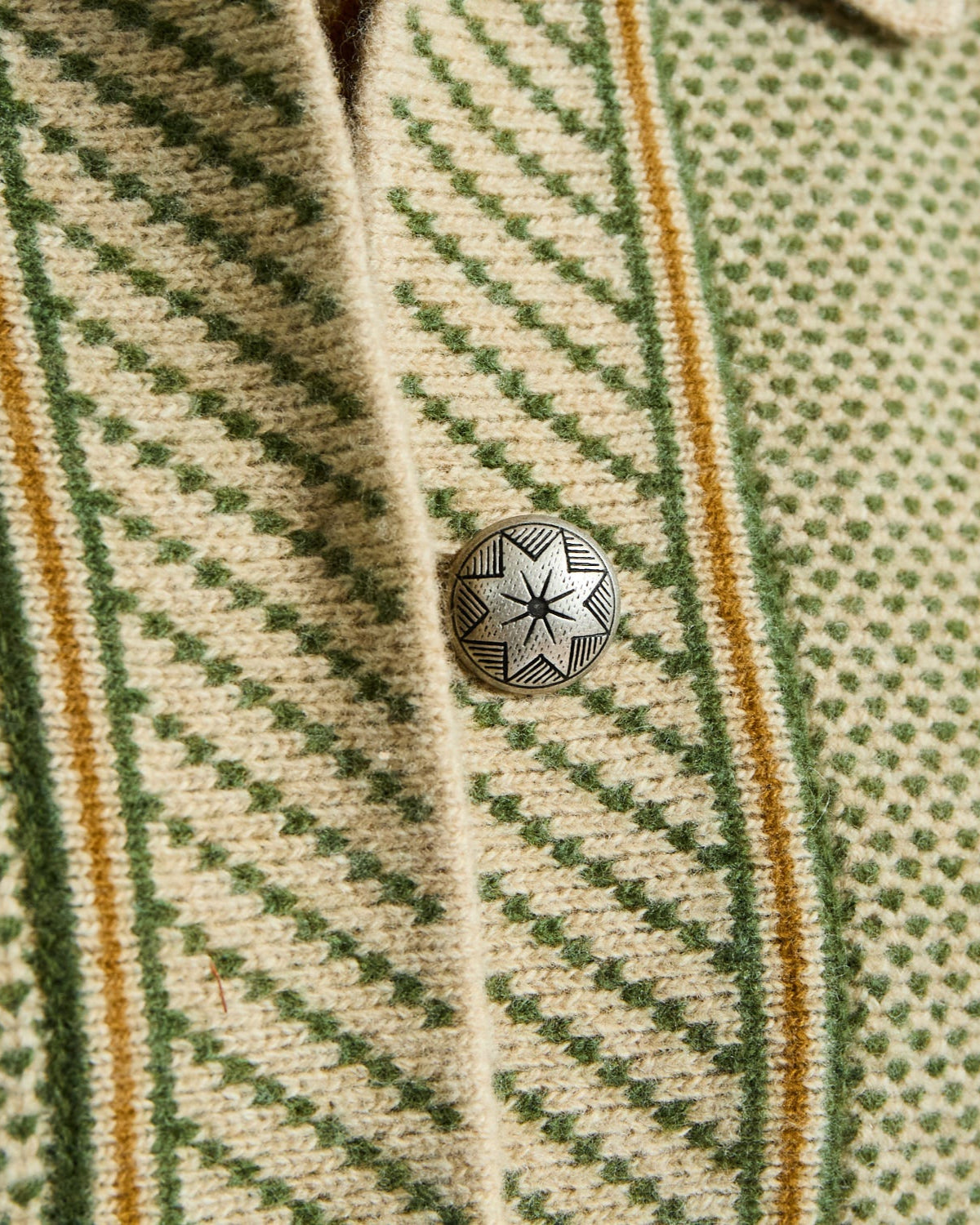 Close-up of a patterned fabric with a button on a green and beige background