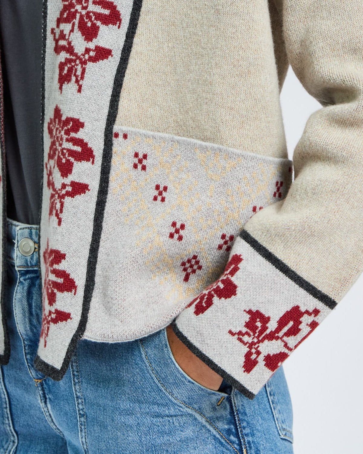 Close-up of a beige jacket with red floral patterns on a plain background