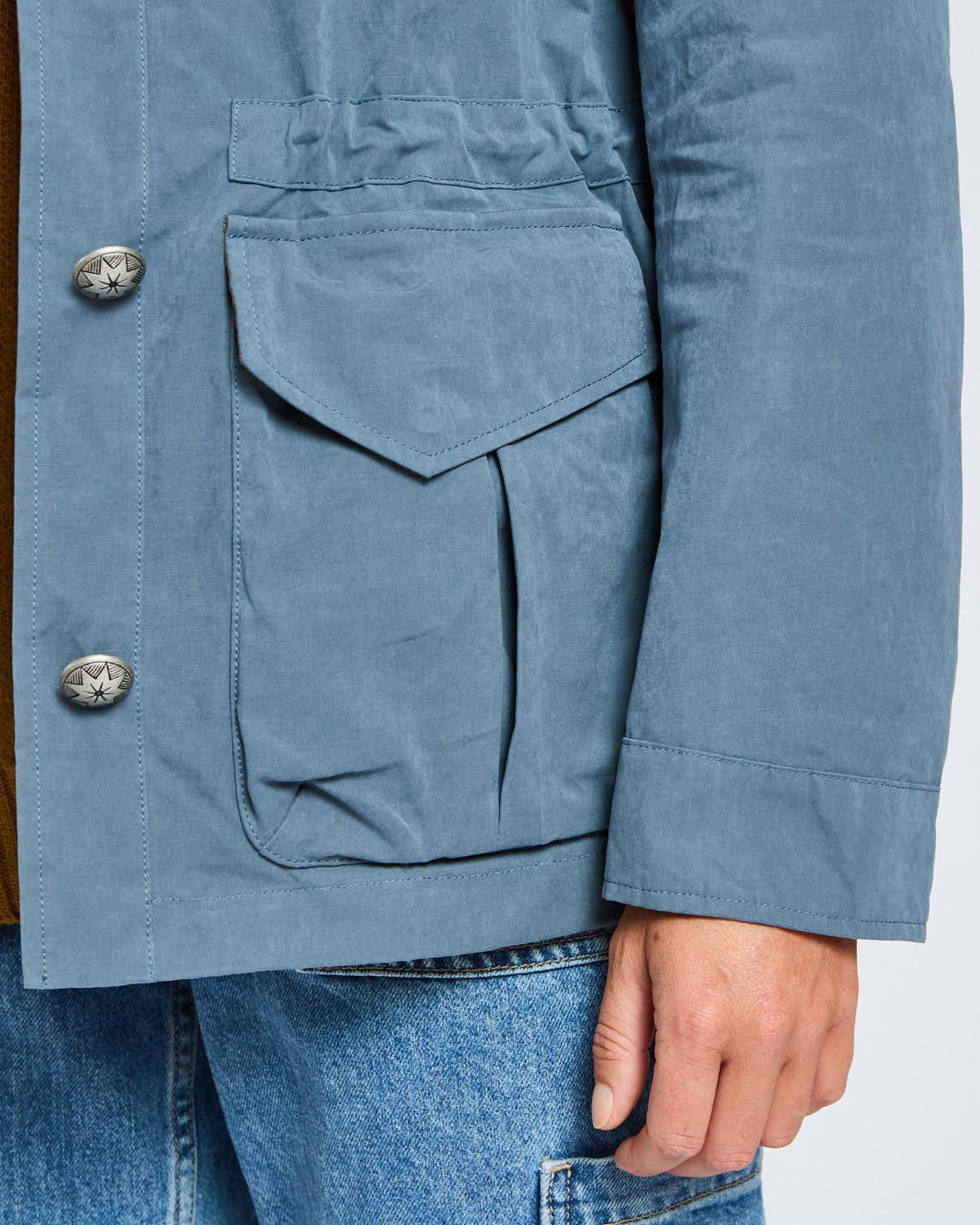 Close-up of a blue jacket with button details on a plain background