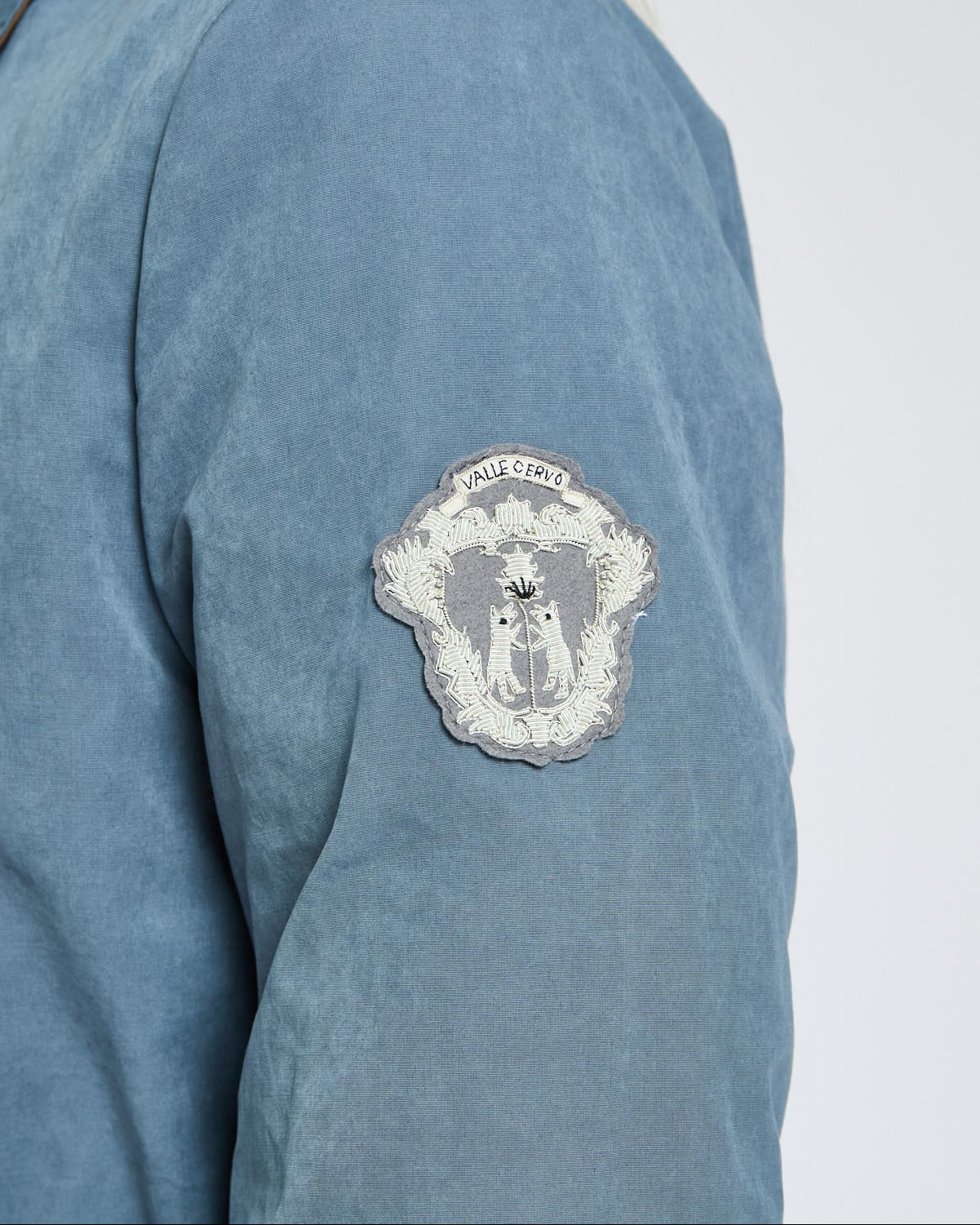 Blue shirt with a patch on the sleeve against a white background