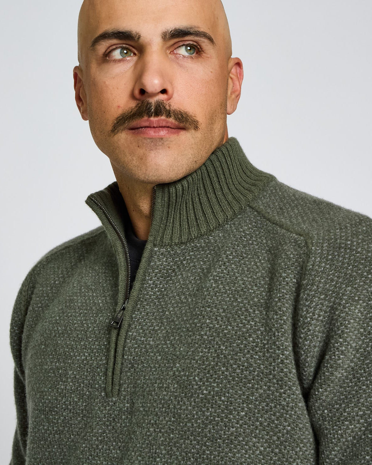 Man wearing a green sweater against a plain background