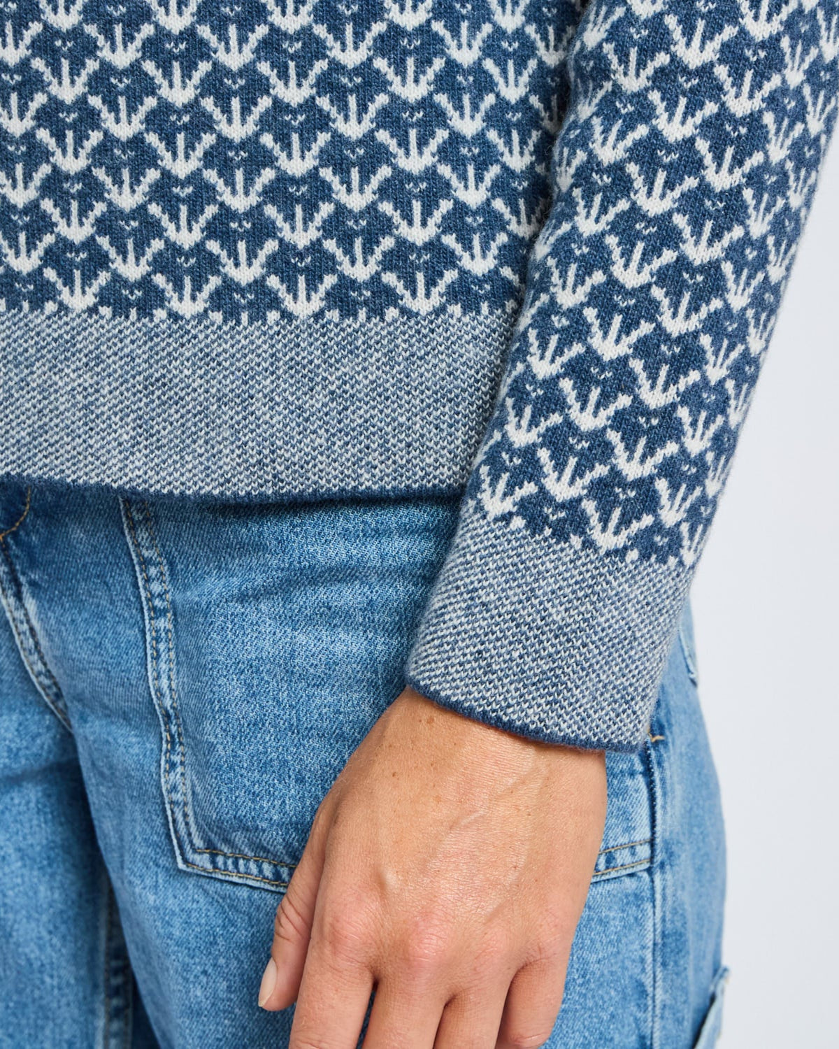 Close-up of a blue patterned sweater and jeans on a plain background