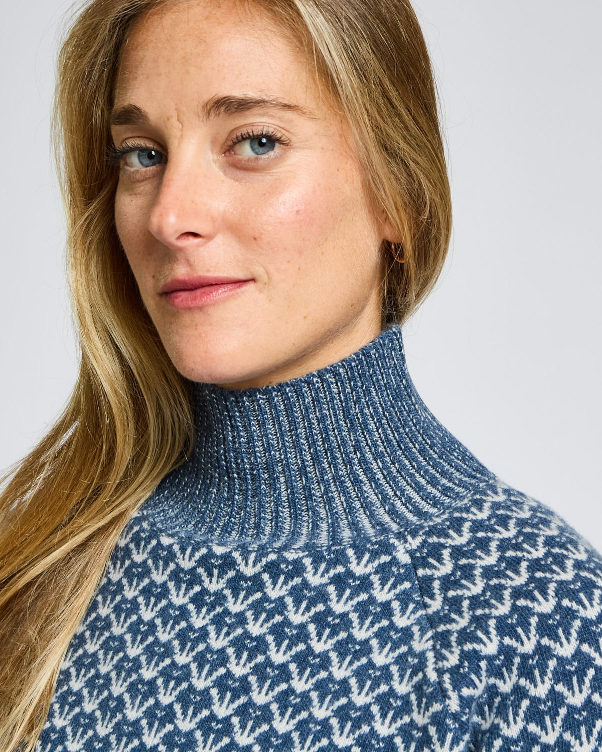 Woman wearing a blue patterned sweater against a plain background