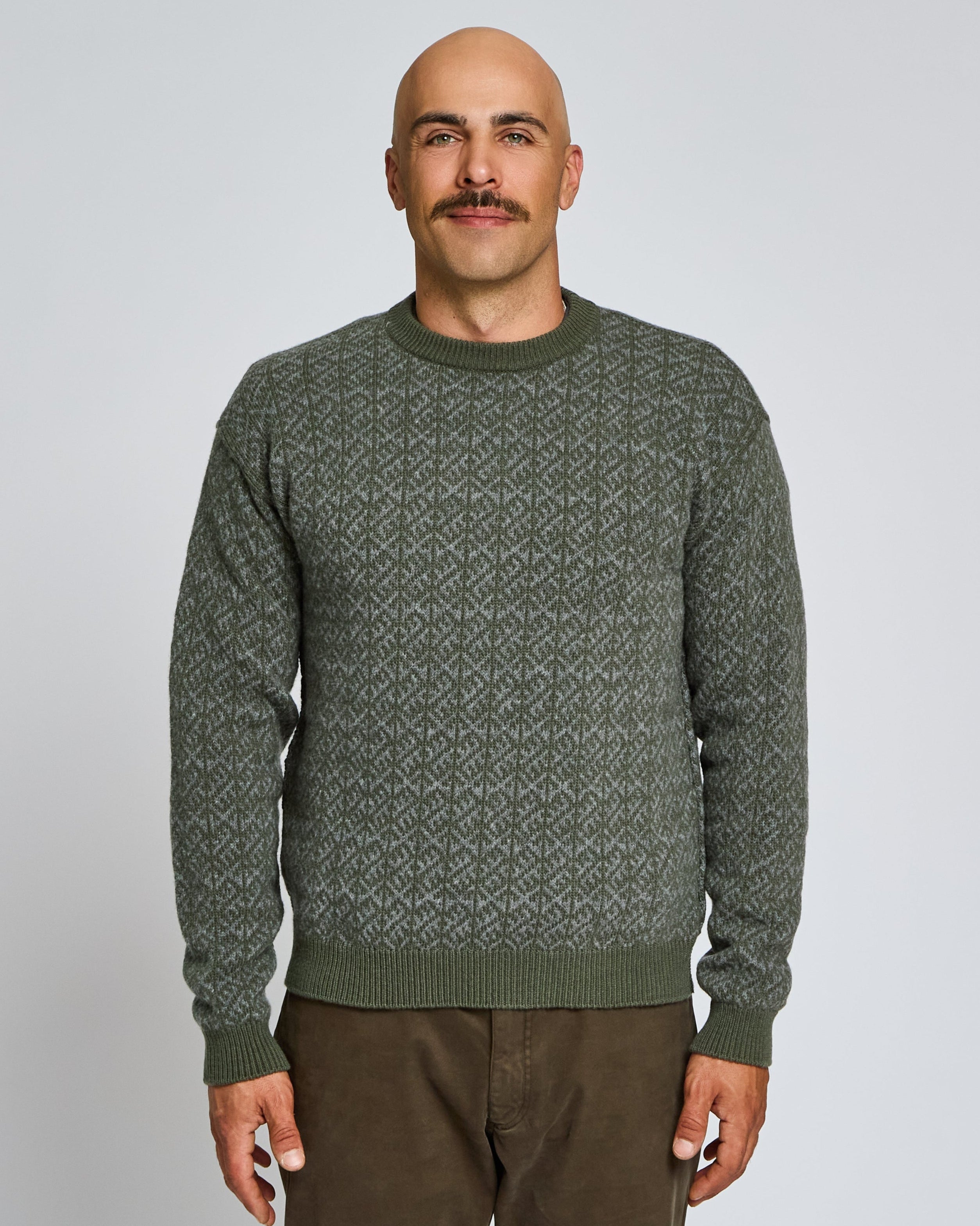 Man wearing a green patterned sweater against a plain background