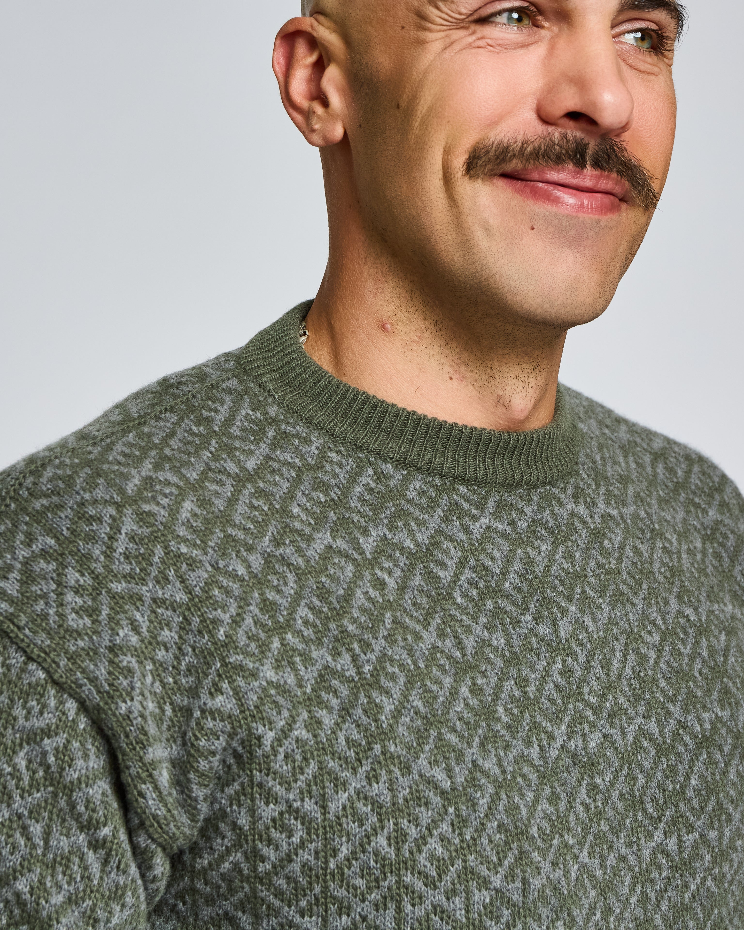 Man wearing a green patterned sweater against a plain background