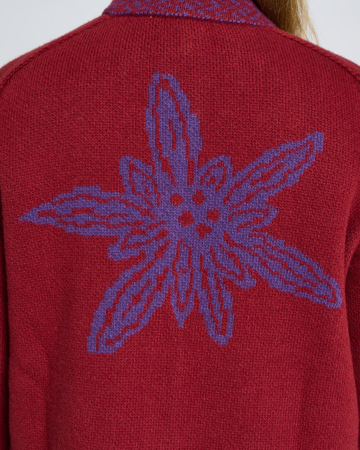Red sweater with a purple floral design on the back against a white background