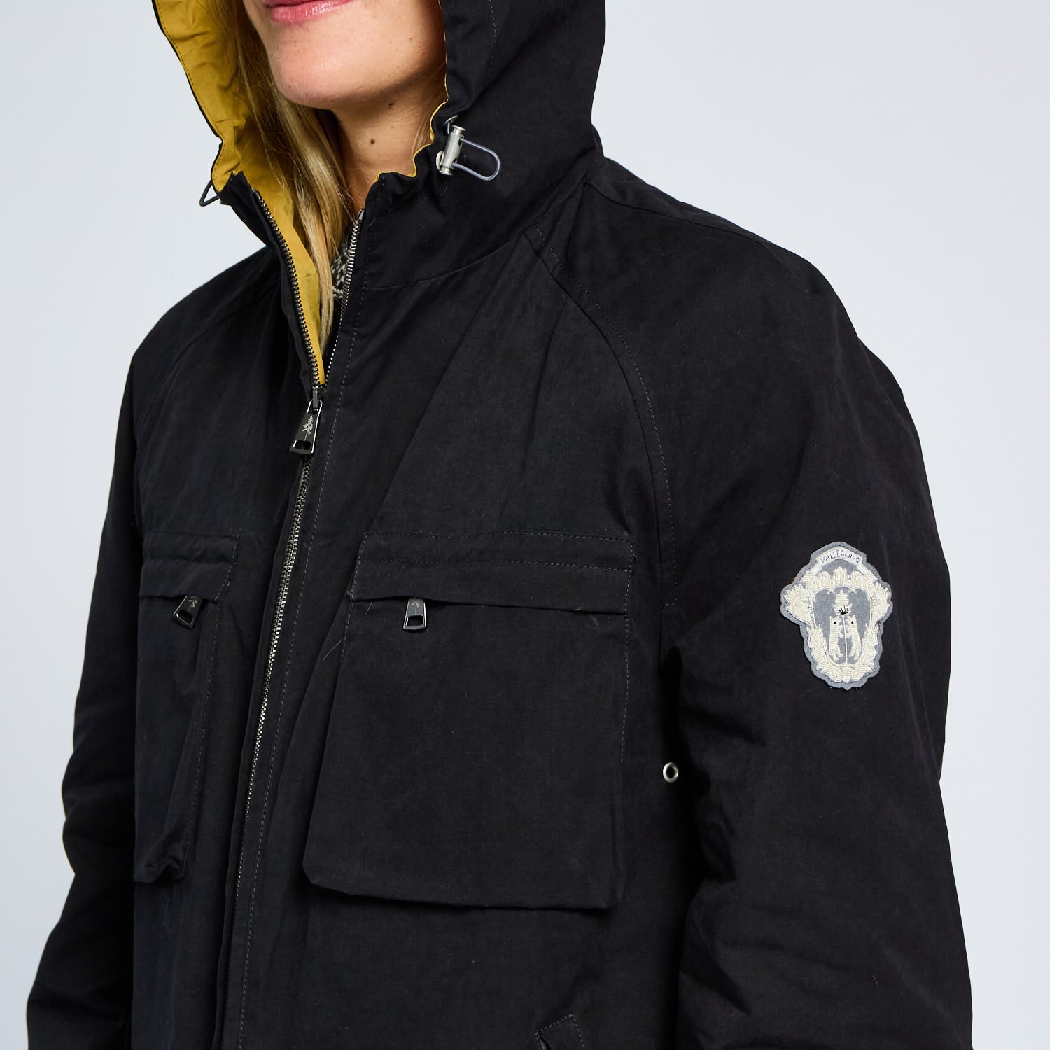 Black jacket with a brand logo on the sleeve against a light gray background