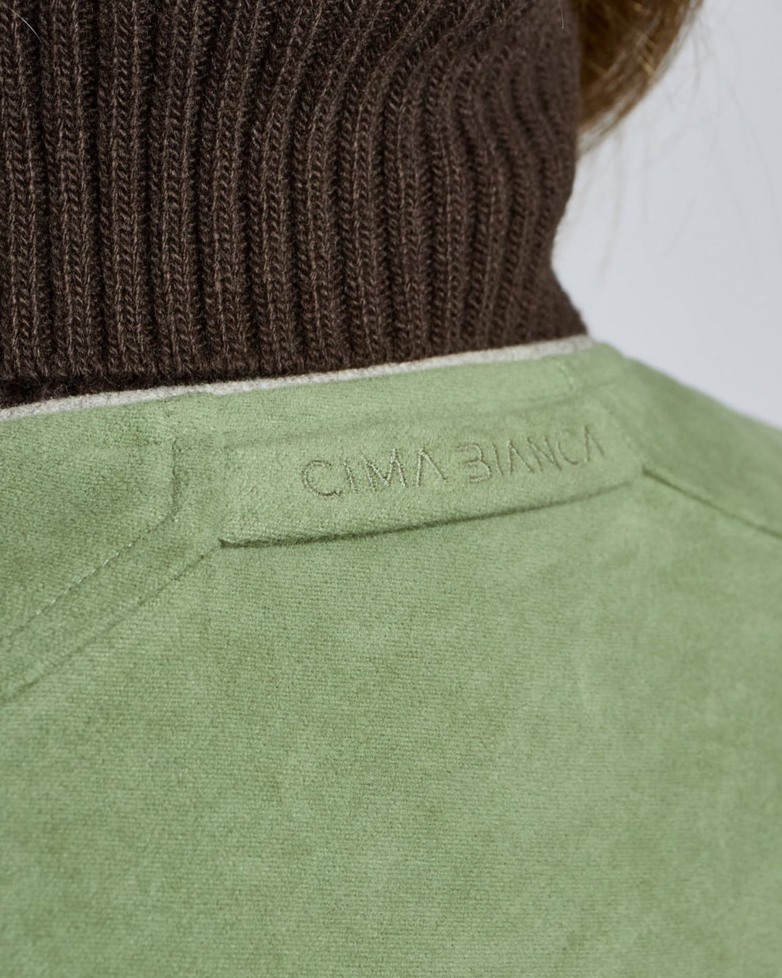Close-up of a green jacket with a brand label on a white background