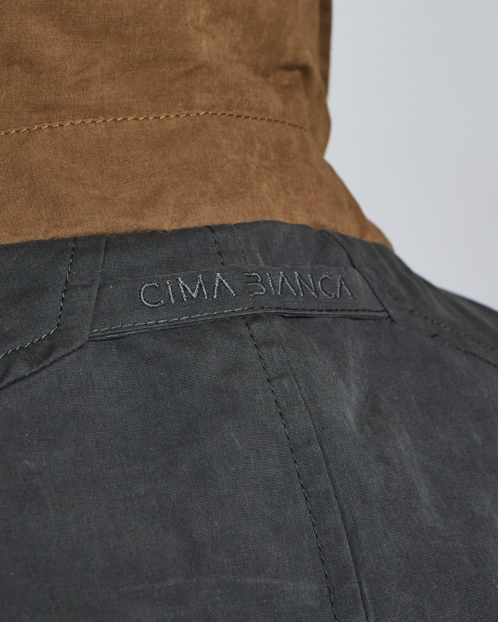 Close-up of a jacket with 'Cima Bianca' branding on a gray background