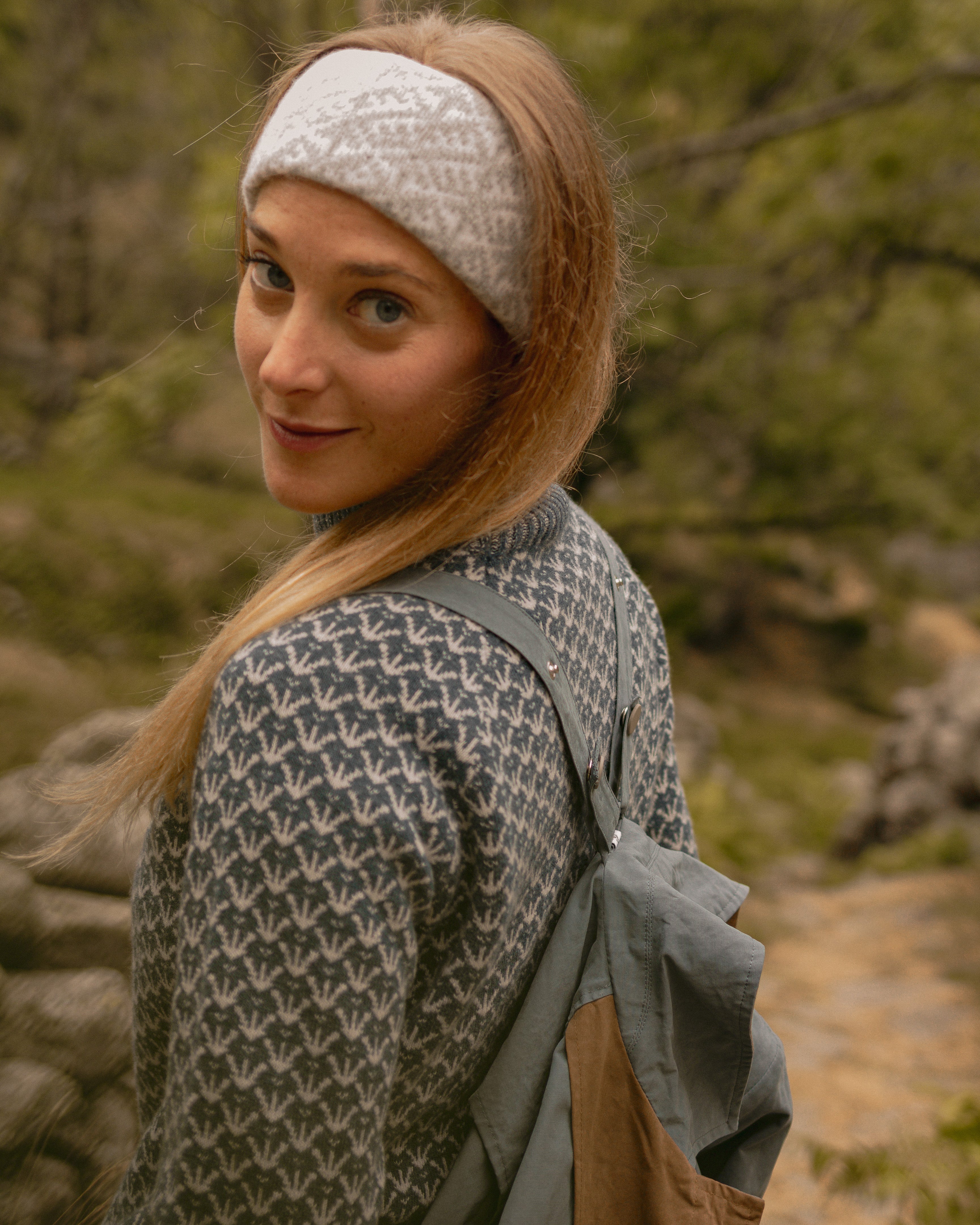 Woman wearing a patterned headband and carrying a backpack in a natural setting