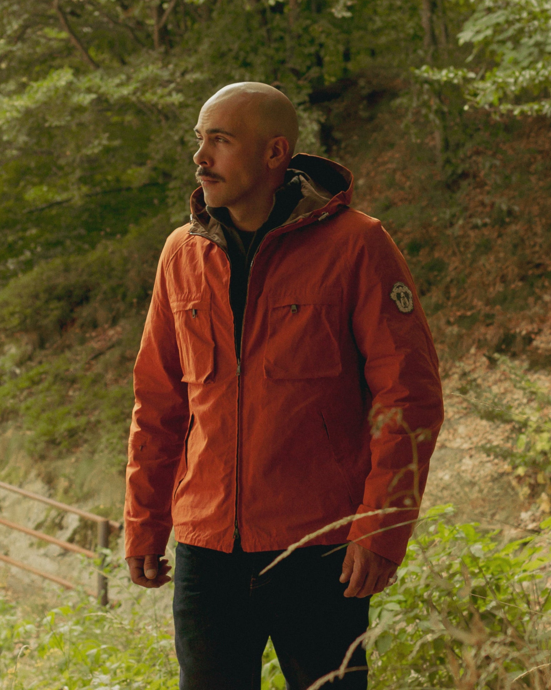 Man in an orange jacket walking on a forest path
