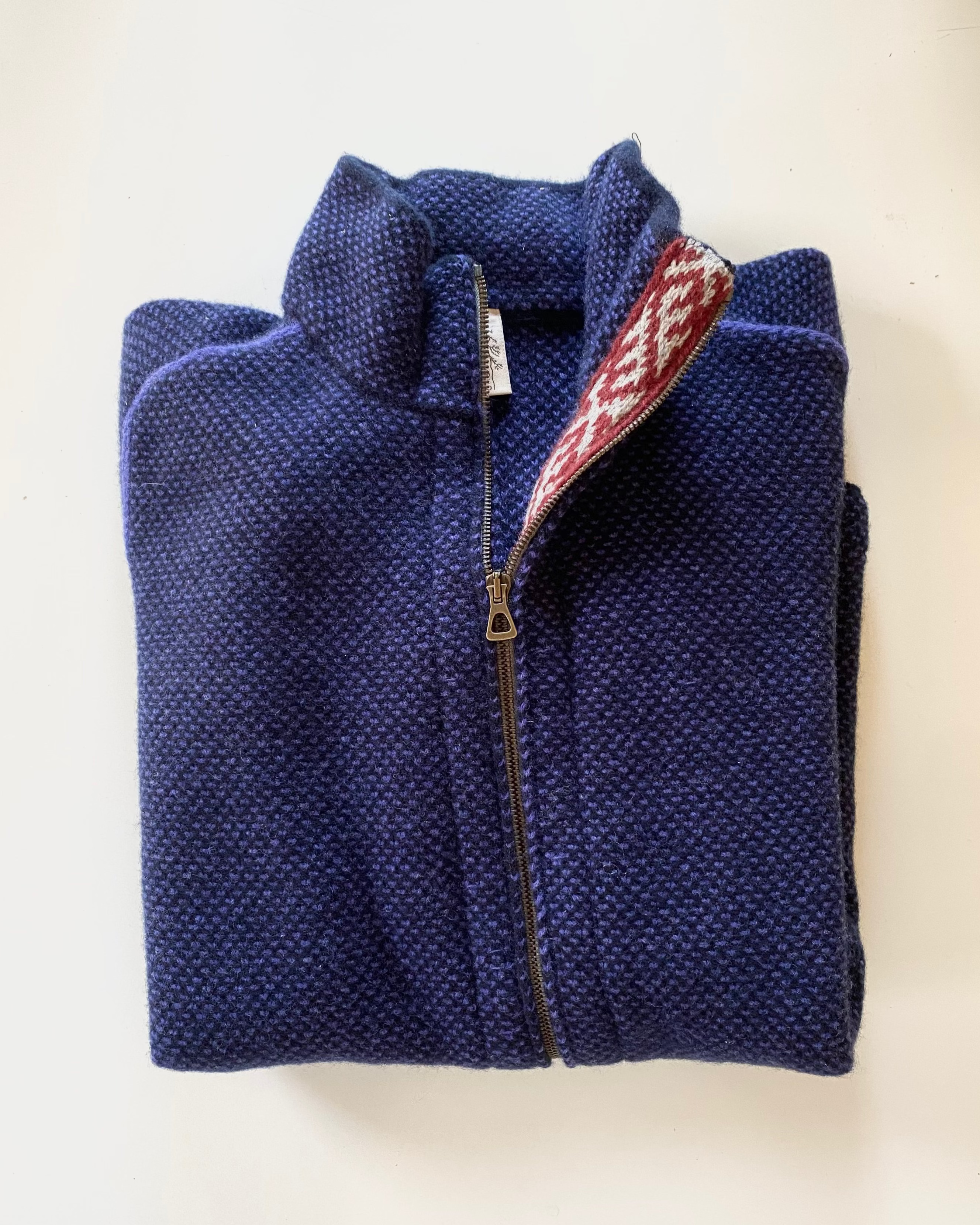 Folded navy blue fleece jacket with a brand logo on a light background