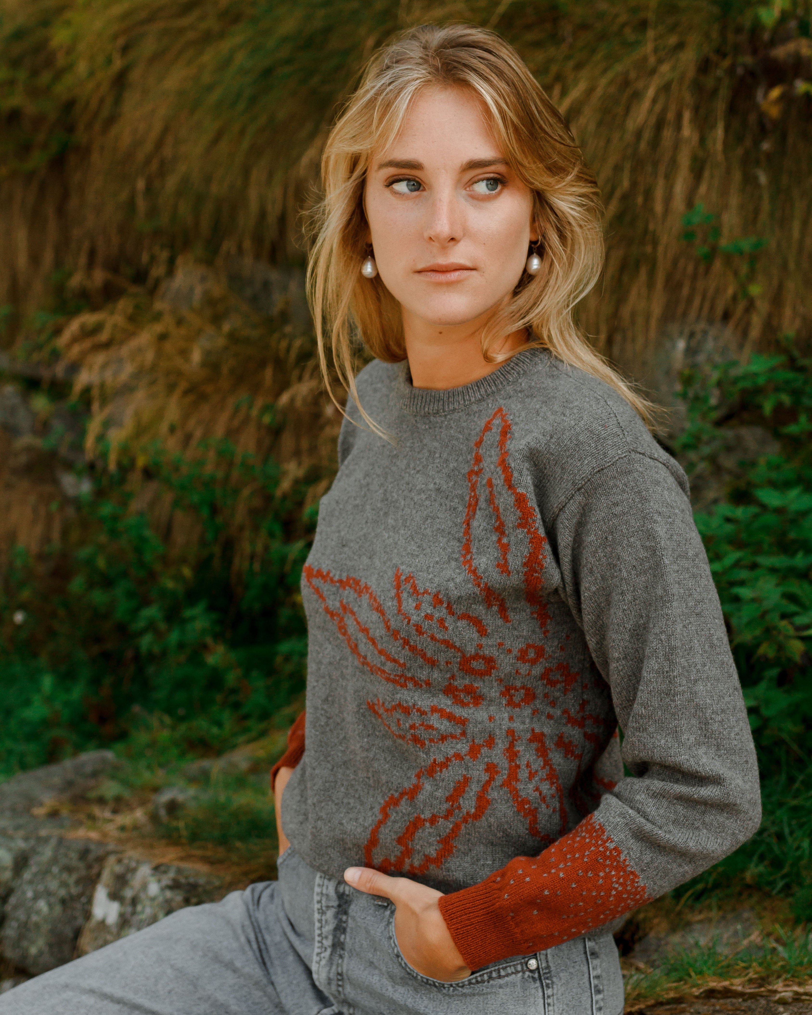 Woman wearing a gray sweater with a red pattern outdoors