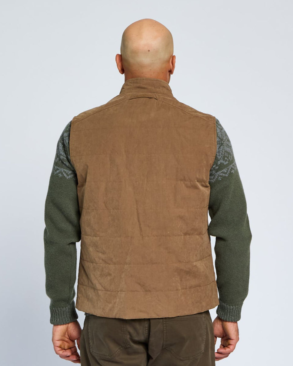 Man wearing a brown vest over a green shirt on a white background