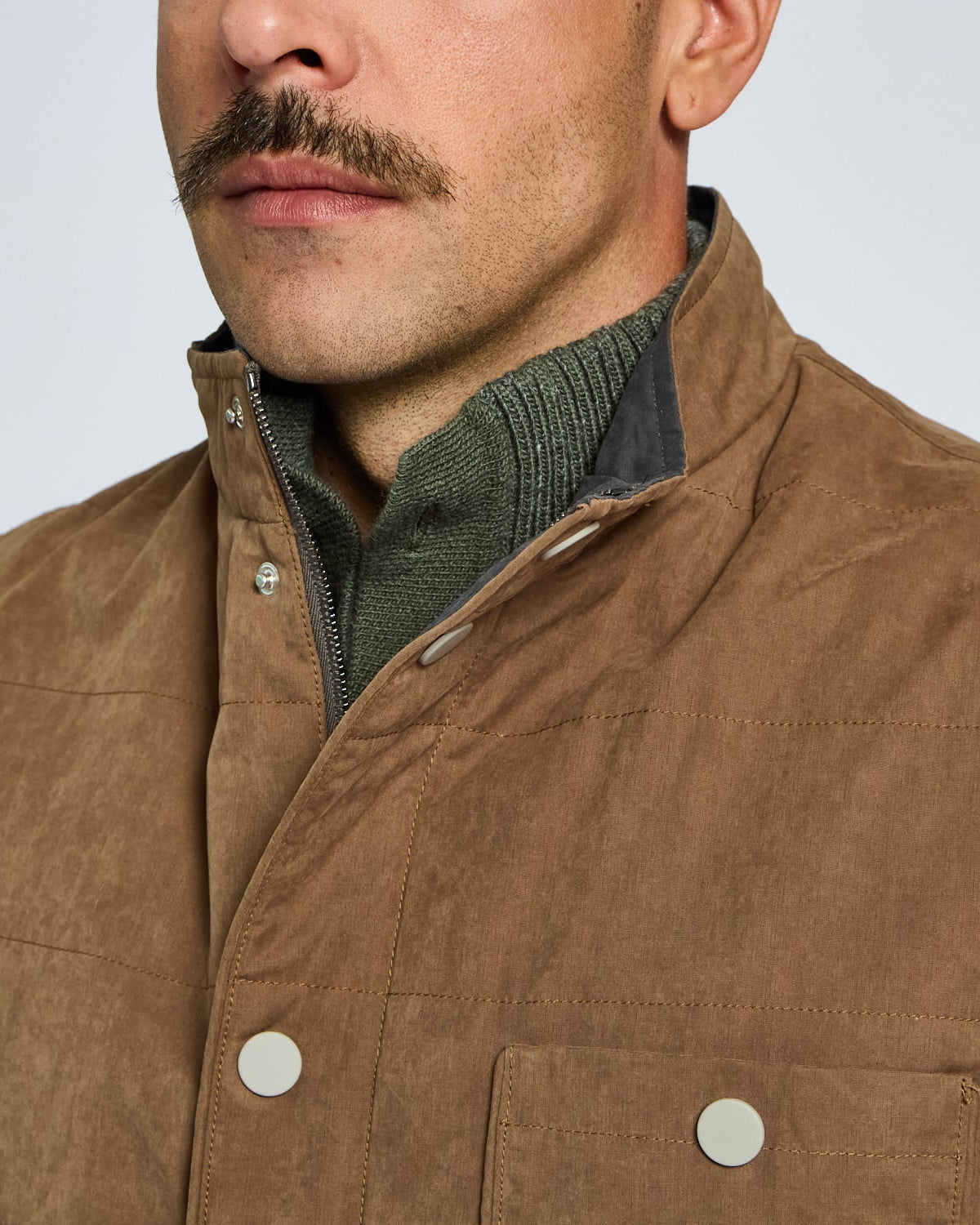 Close-up of a brown vest worn by a person with a neutral background