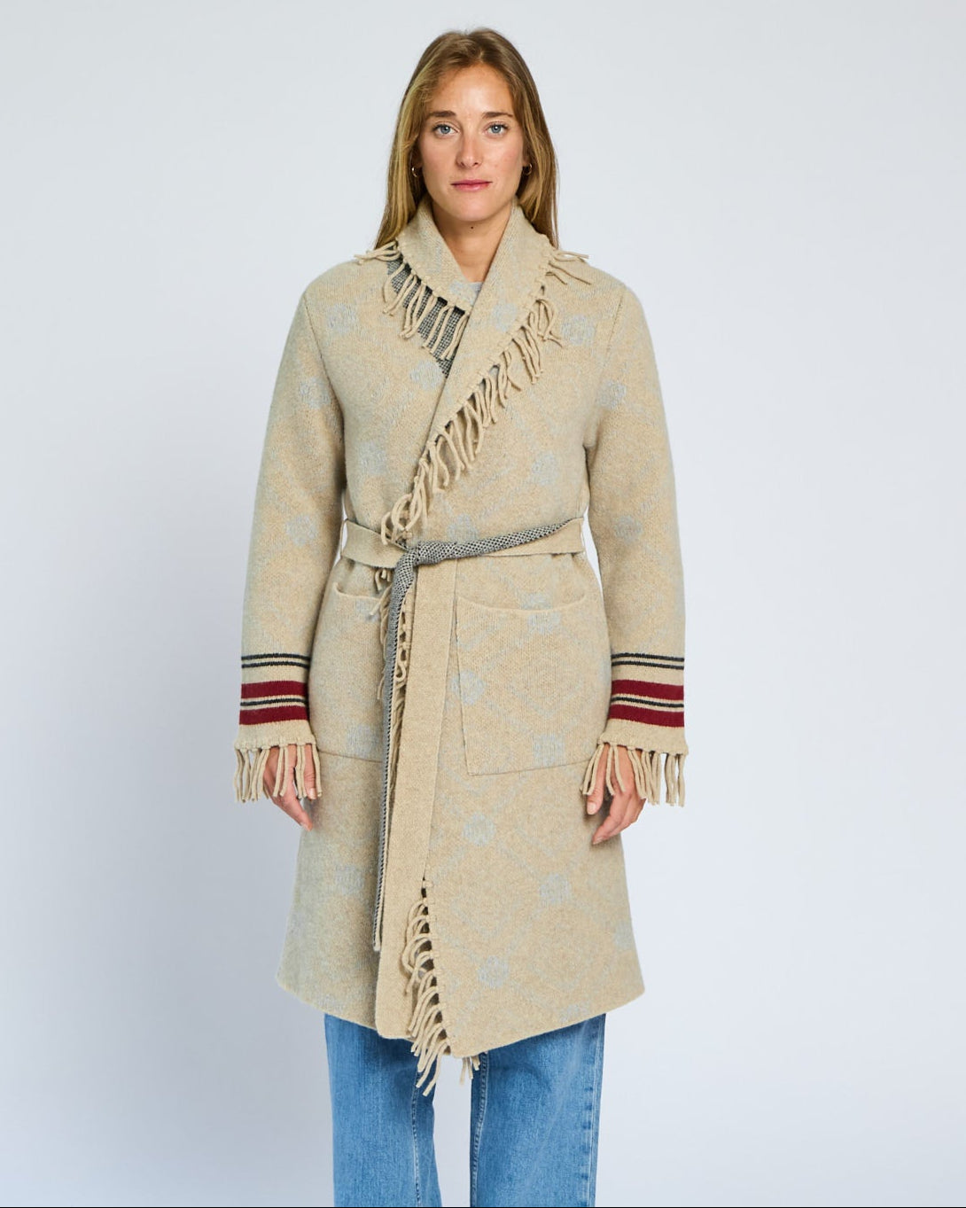 Woman wearing a beige coat with fringe details on a white background