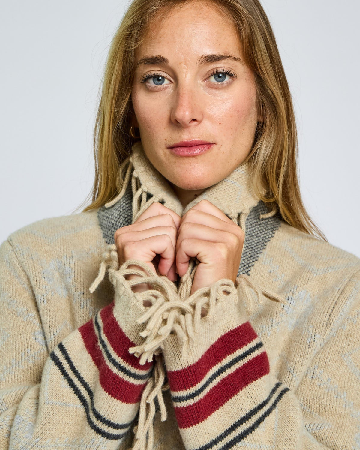 Woman wearing a plaid scarf with a red and blue stripe against a plain background