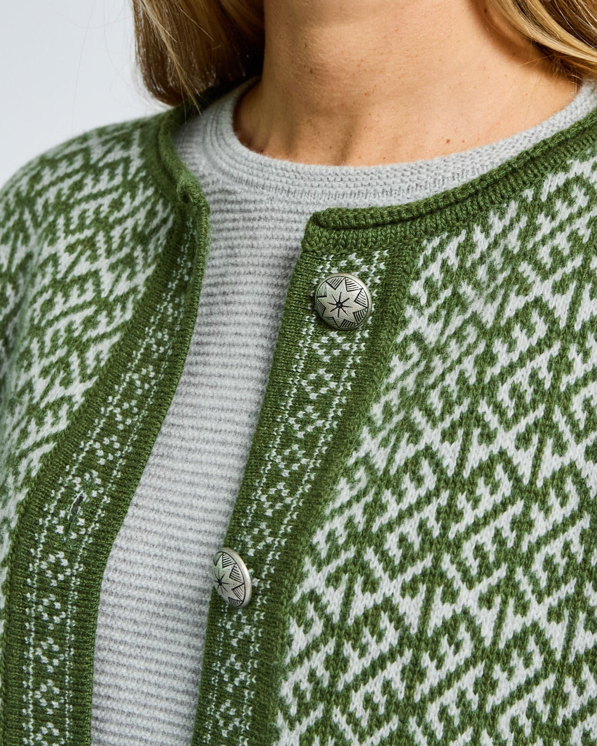 Green patterned cardigan with silver buttons on a light gray background