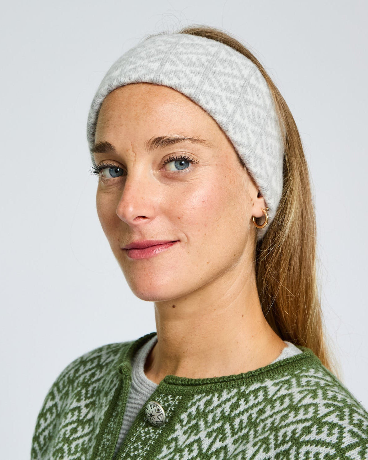Woman wearing a white knitted headband against a plain background