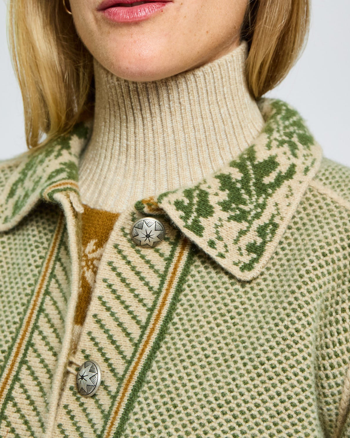 Close-up of a person wearing a patterned coat with a turtleneck sweater underneath.
