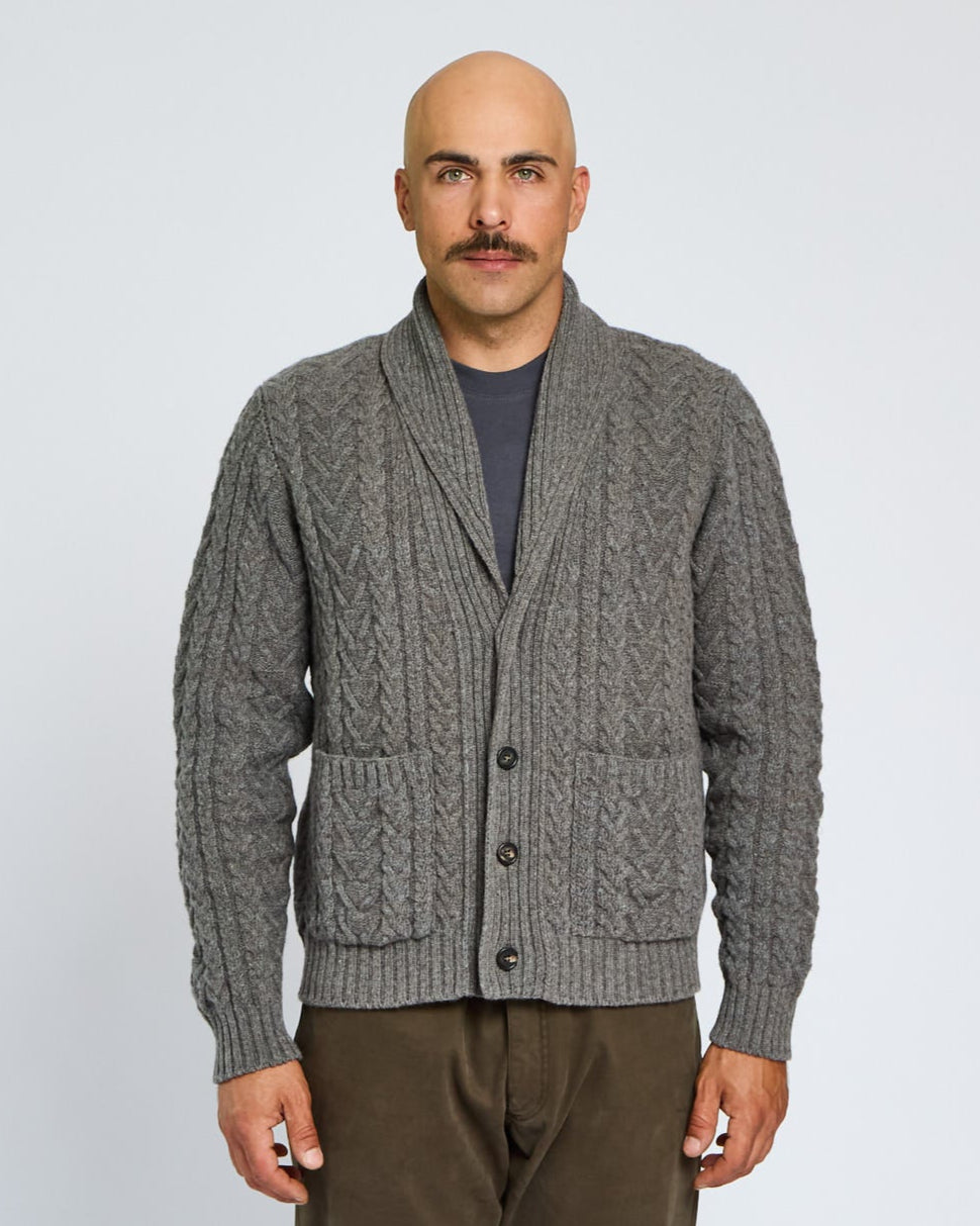 Man wearing a gray cable knit cardigan on a light gray background