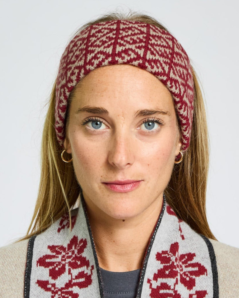 Woman wearing a red and white patterned headband and scarf against a plain background