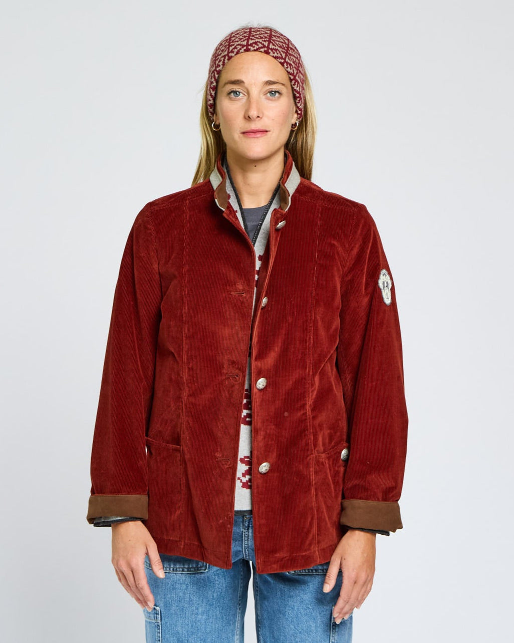Person wearing a red jacket and blue jeans on a plain background