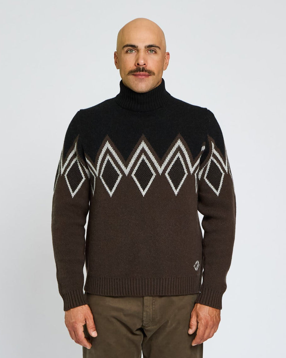 Man wearing a brown sweater with geometric patterns on a plain background