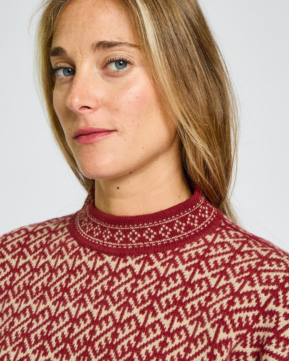 Woman wearing a red and white patterned sweater against a plain background
