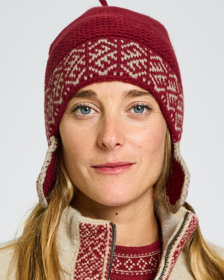 Person wearing a red and beige patterned hat and sweater on a white background