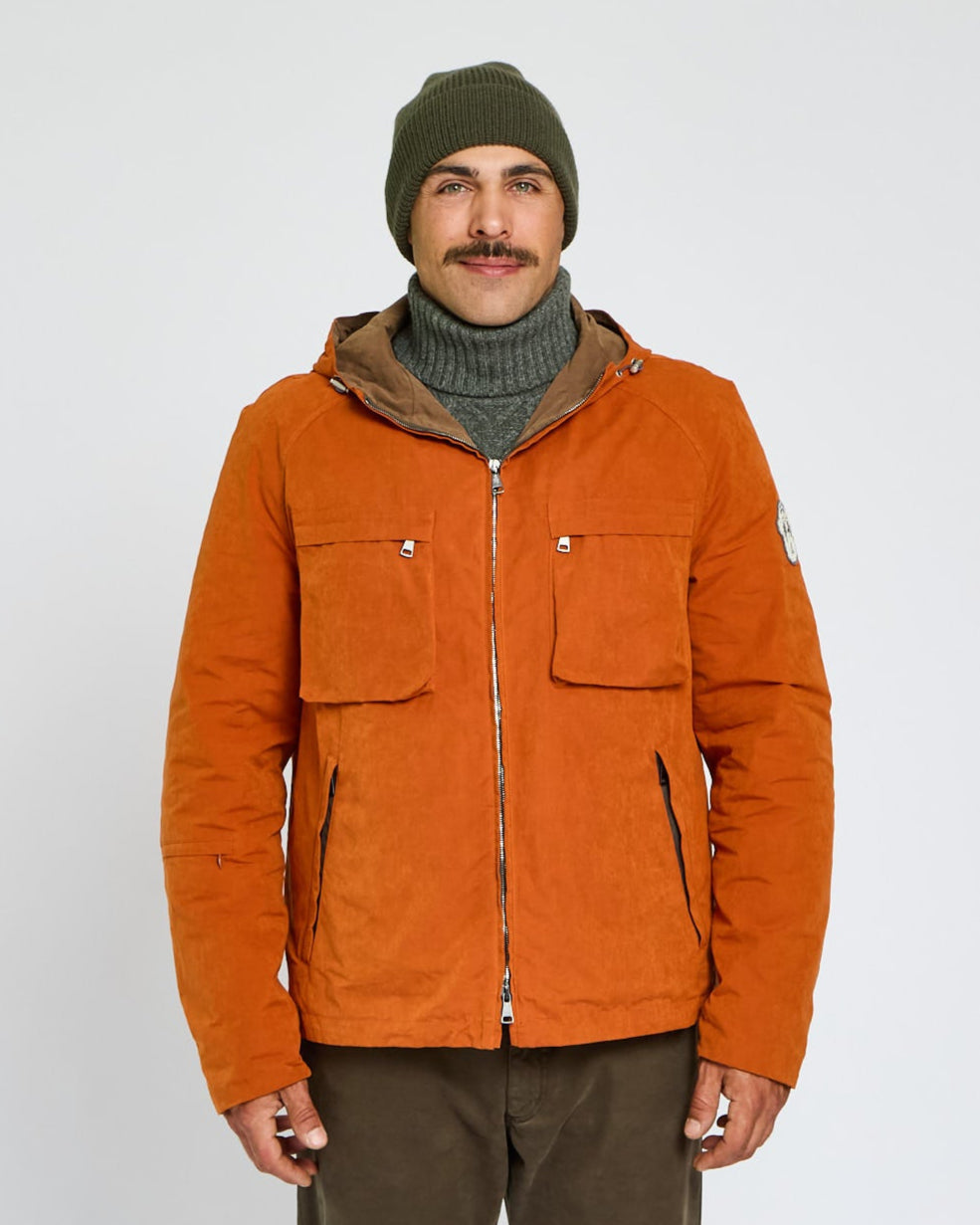 Man wearing an orange jacket with a hood on a white background