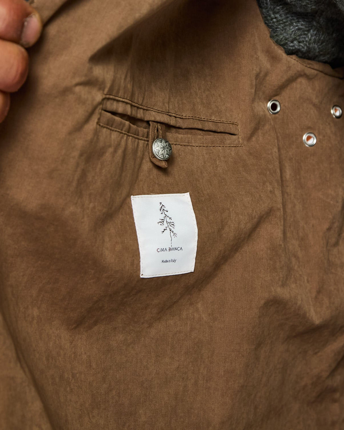 Close-up of a brown jacket with a brand label on a pocket.