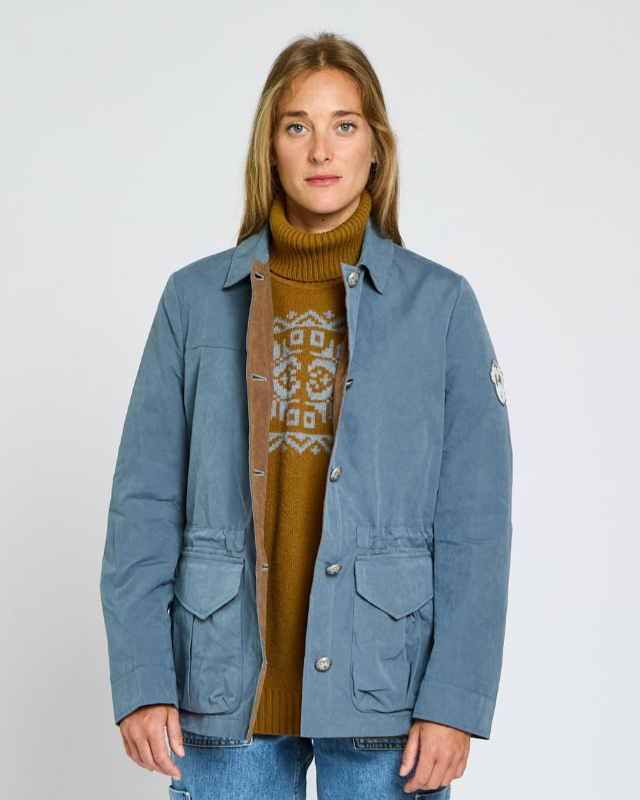 Person wearing a blue jacket over a brown sweater on a white background