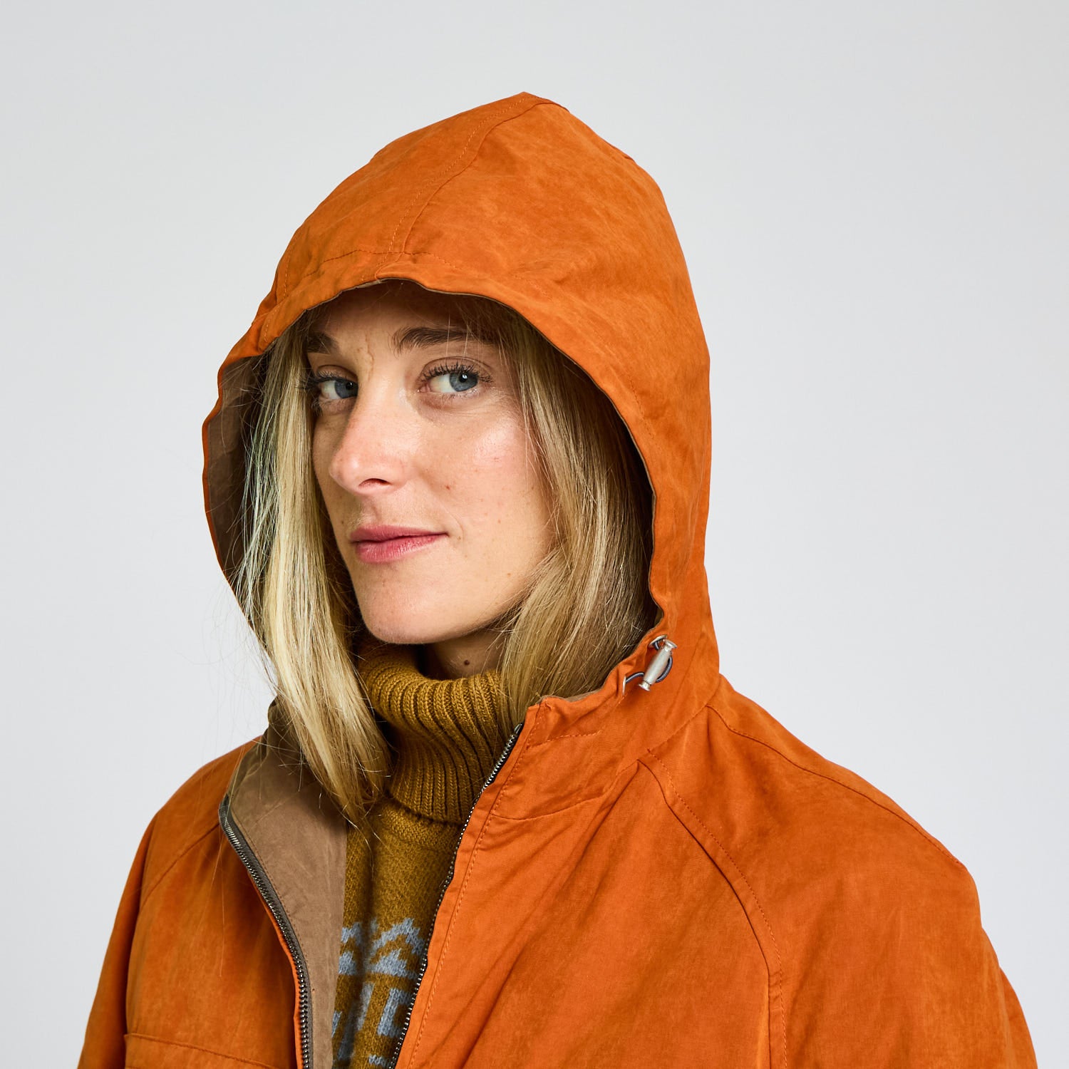 Person wearing an orange hooded jacket on a plain background