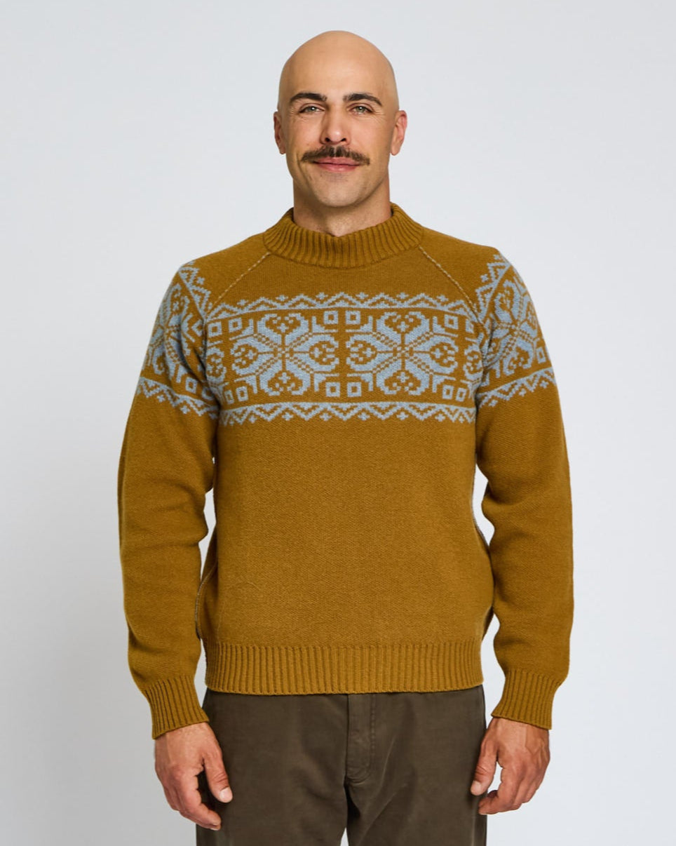 Man wearing a mustard yellow sweater with a patterned neckline against a white background