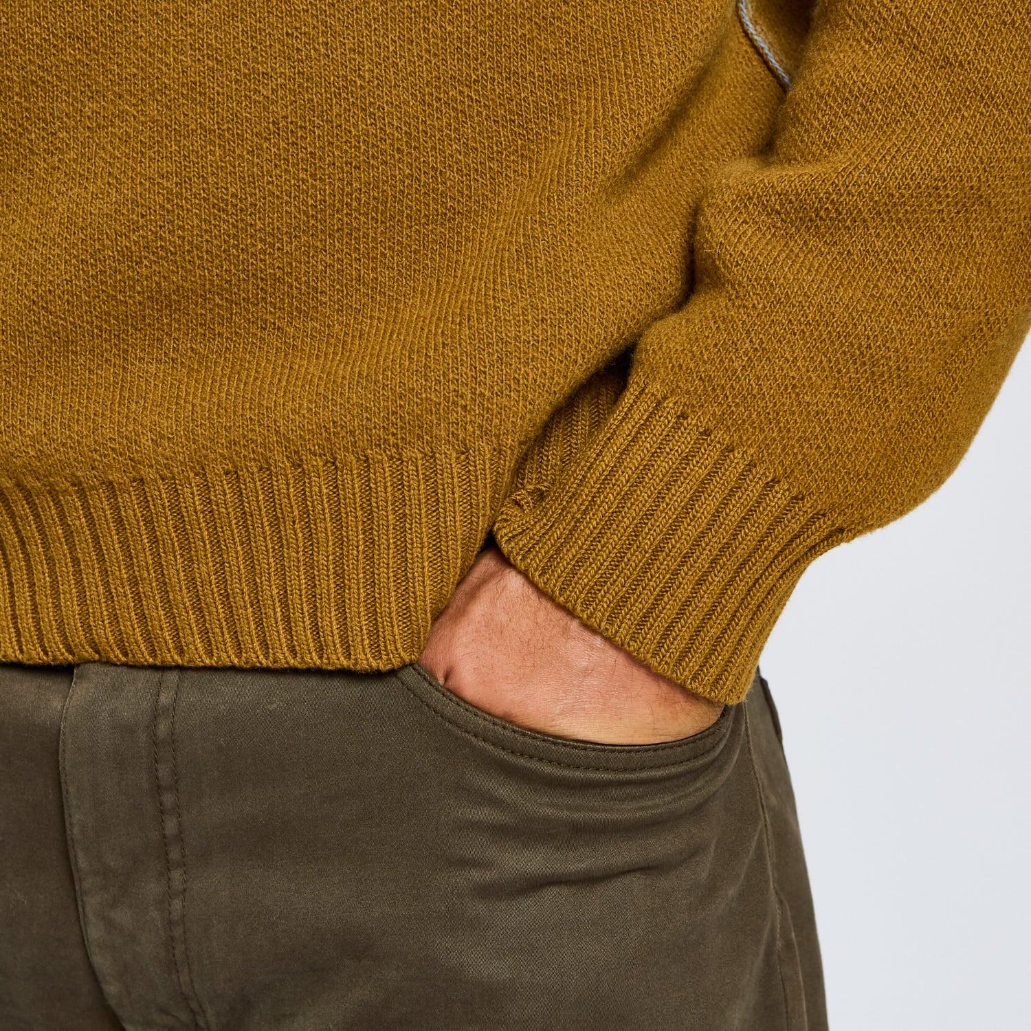 Close-up of a mustard yellow sweater and green pants on a white background