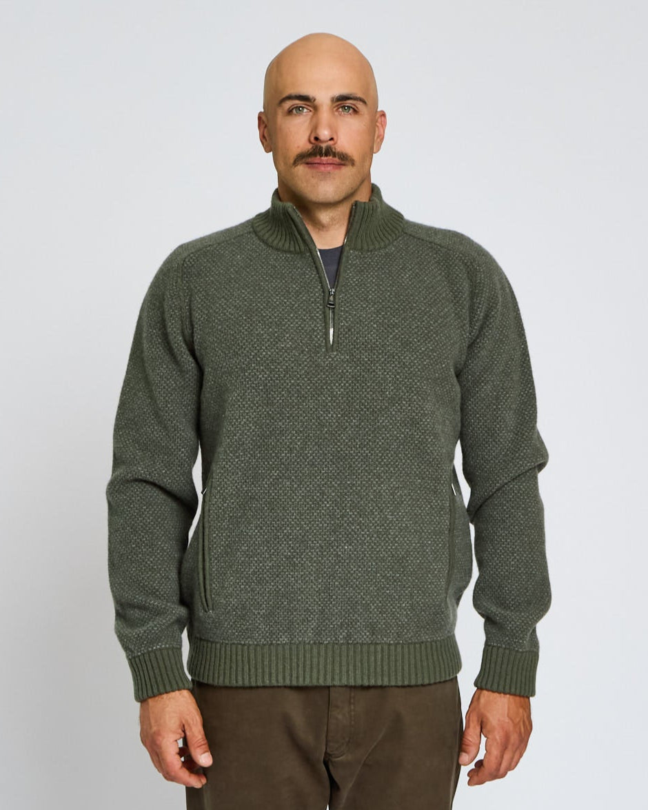 Man wearing a green sweater against a plain background