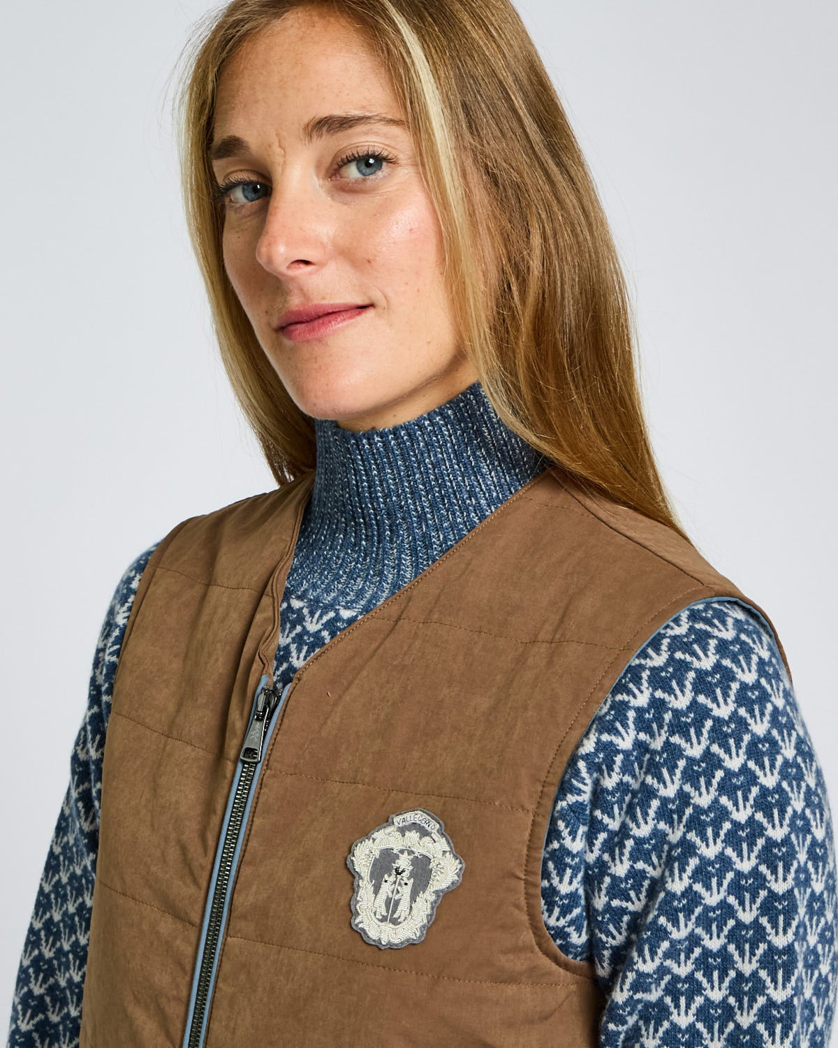Woman wearing a brown vest with a logo on a white background