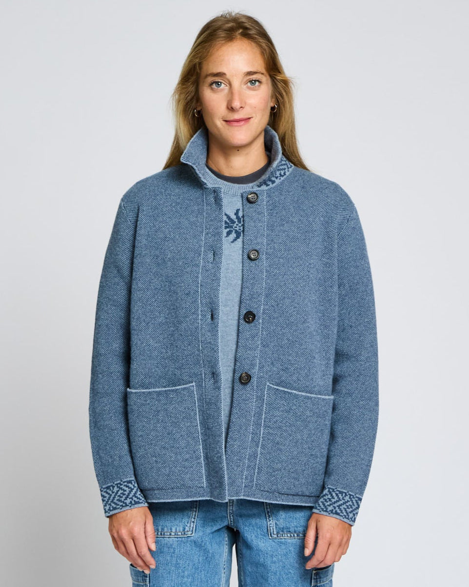 Person wearing a blue jacket with decorative patterns on a light gray background