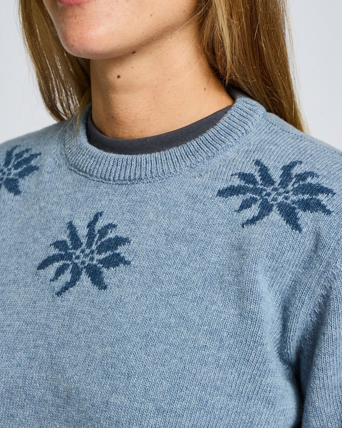 Close-up of a blue sweater with floral patterns on a plain background