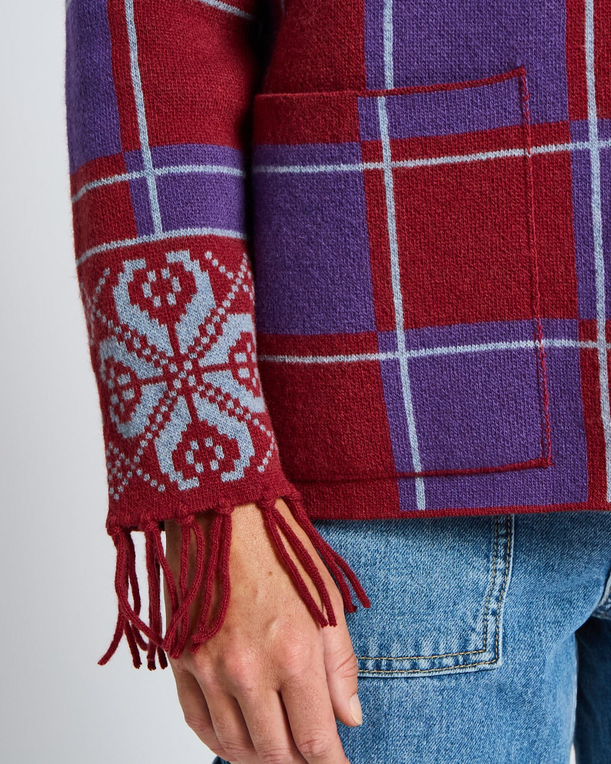 Red and purple plaid jacket with a patterned sleeve and blue jeans on a light gray background