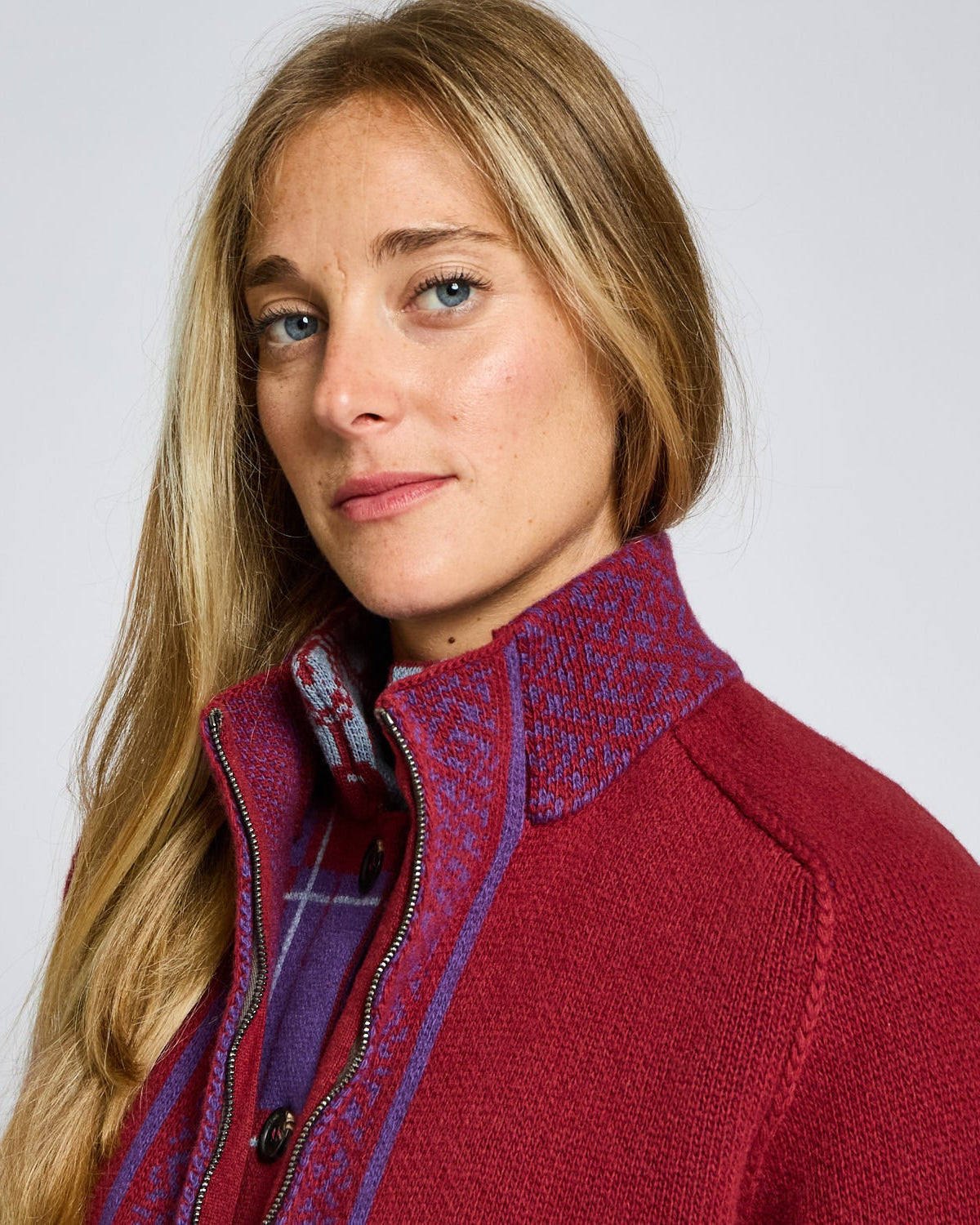 Woman wearing a red jacket with a patterned collar against a plain background