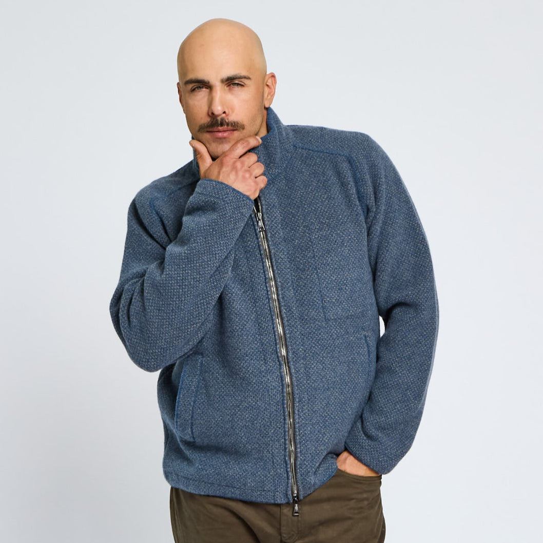 Man wearing a blue zip-up sweater against a plain background