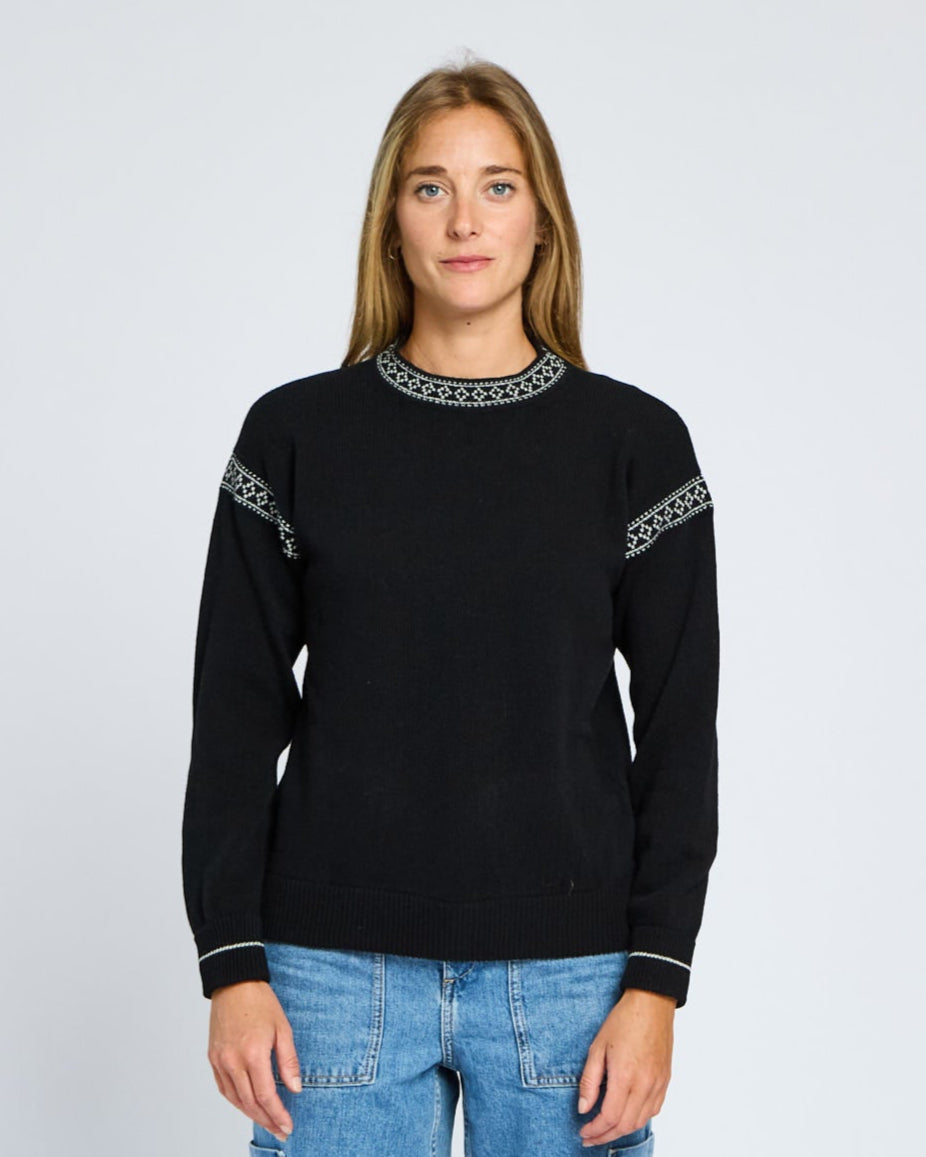 Person wearing a black sweater with white patterns on a light gray background