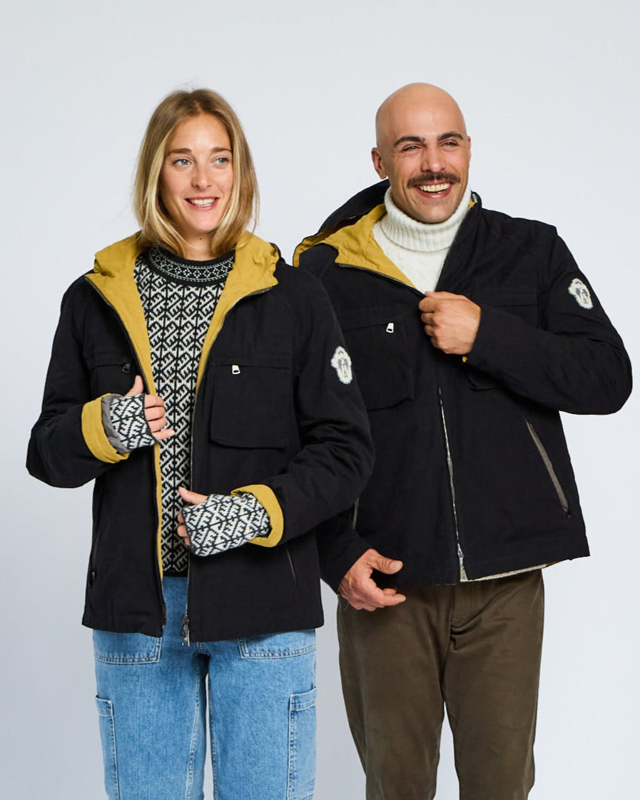 Two people wearing matching black jackets with yellow accents on a white background