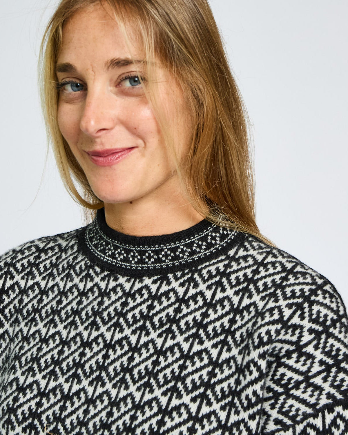 Woman wearing a black and white patterned sweater against a plain background