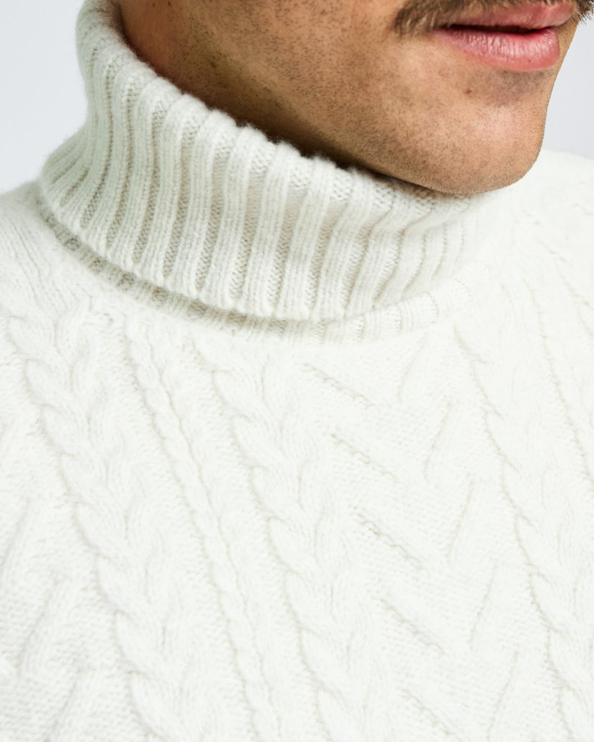 Close-up of a person wearing a white turtleneck sweater.